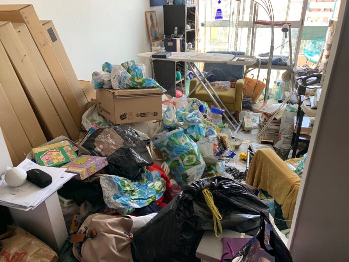 Pièce encombrée avec de nombreux sacs et objets accumulés nécessitant un débarras et un nettoyage.